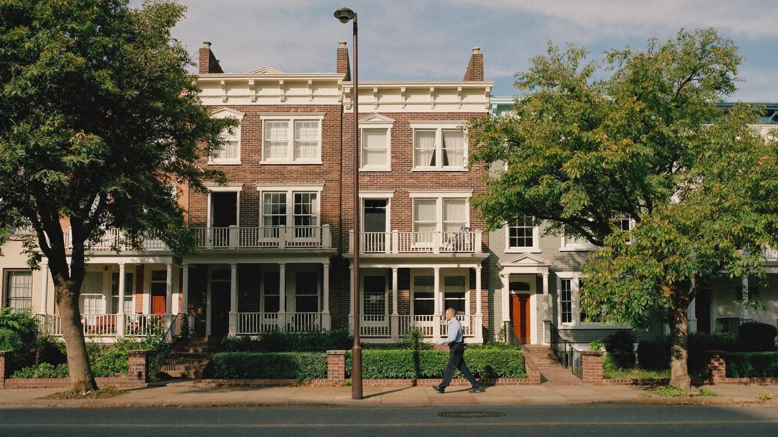 Landlord weighing property management options on the porch of a historic rowhouse in Richmond, Virginia